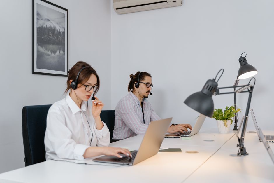 Dos agentes de soporte trabajando con laptops y audífonos