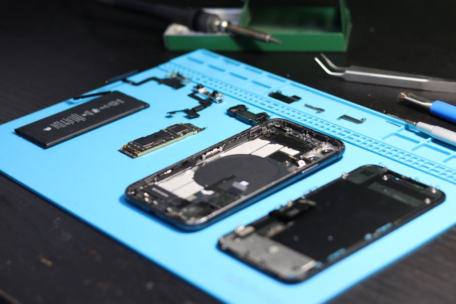 Smartphone desarmado con herramientas sobre una mesa de trabajo, enfocado en reparación y tecnología