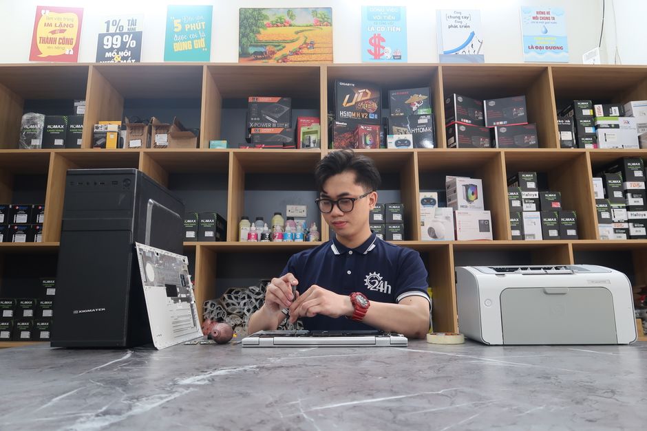 Joven técnico reparando una computadora en una tienda de electrónica moderna.