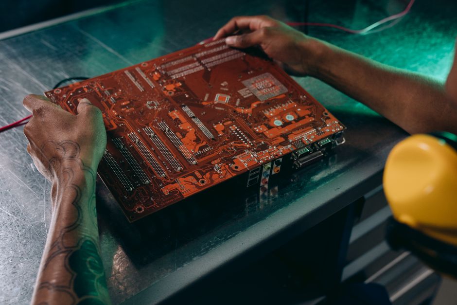 Primer plano de un técnico trabajando en una placa de circuito en un entorno industrial.