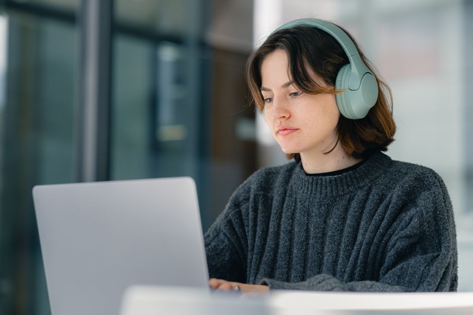 Técnica de soporte remoto trabajando concentrada en una laptop con auriculares
